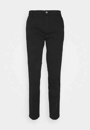Pantalones negros ajustados con cierre frontal de botón y cremallera, trabillas para cinturón y bolsillos laterales sobre un fondo blanco.