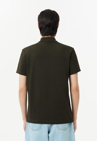 Mörkgrön kortärmad polo skjorta med klassisk krage, tillverkad av slätt material, med en ren design utan synliga mönster eller detaljer.