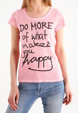 Vaaleanpunainen, lyhythihainen puuvillainen T-paita, jossa on mustat, paksut tekstit "Do MORE of what makes you happy." Klassinen istuvuus, rento muotoilu.