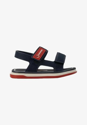 Sandalo blu navy per bambino con dettagli rossi e bianchi, cinturini regolabili e suola piatta con fondo rosso.