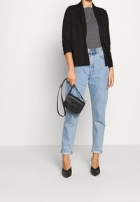 Svart blazer, randig skjorta, ljusblå högmidjade jeans, svarta klackar och en liten svart handväska. Slät tyg och strukturerad design.