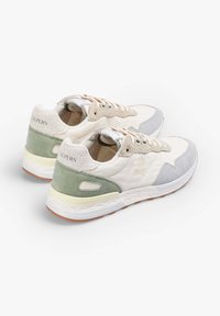 Un par de zapatillas off-white con tacón de ante verde, punta gris claro, cordones beige y logotipo de calavera en el lateral, sobre un fondo blanco.