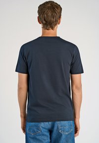 Navyblå kortärmad t-shirt med rund halsringning, tillverkad av bomullsblandning. Slät textur, enkel design. Bärs med ljusblå denimjeans.