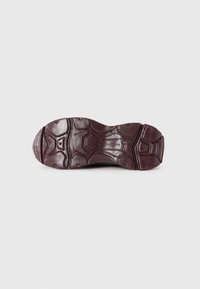 Semelle de chaussure de sport bordeaux en caoutchouc texturé, dotée d'un motif de semelle pour une meilleure adhérence. Design incurvé et bords renforcés visibles.
