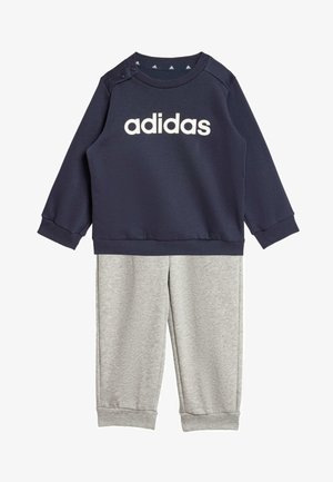 Sudadera navy con el logotipo "adidas" en blanco, con snaps en los hombros; combinada con pantalones gris claro, ambos en un tejido suave y texturizado.