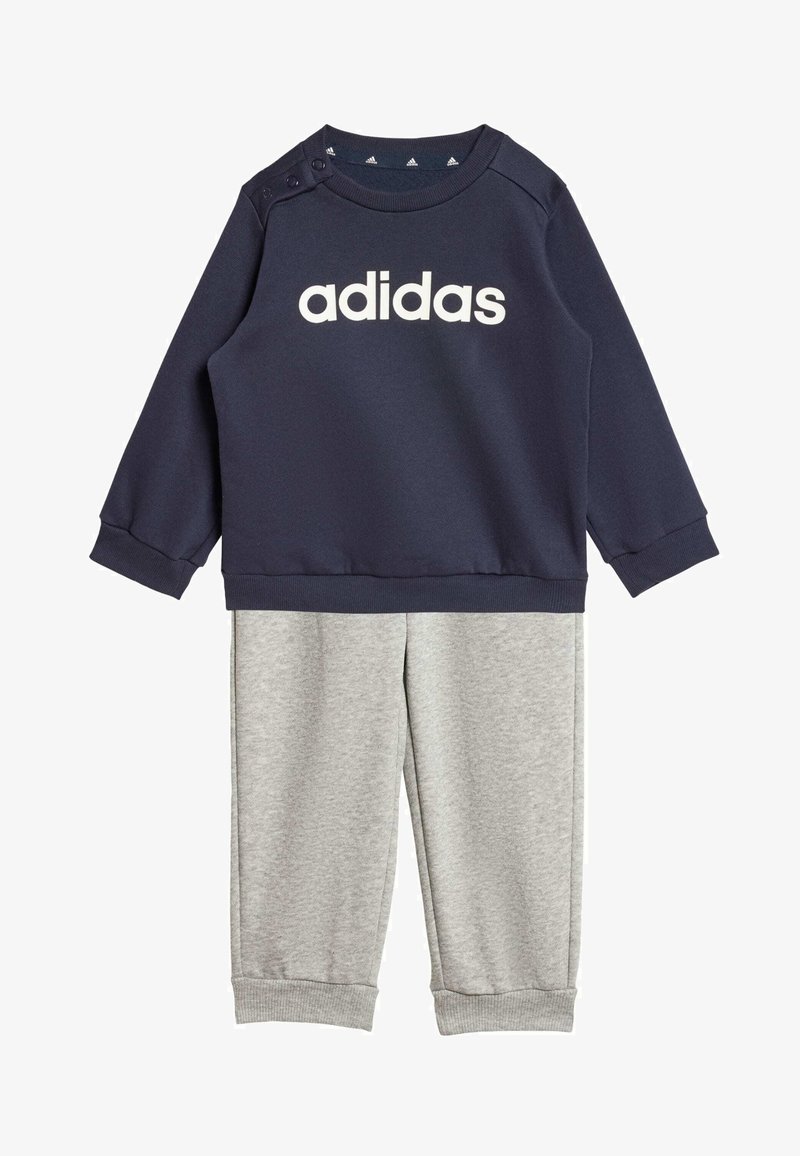 Sweat-shirt navy avec le logo "adidas" blanc, présentant des boutons-pression aux épaules ; associé à un pantalon gris clair, les deux en tissu doux et texturé.