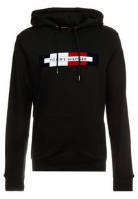 Svart huvtröja med luva, med en färgblockerad logga i rött, vitt och marinblått. Tillverkad av mjukt material med dragsko och en framficka.