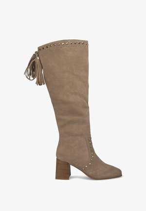 Botte en suédine beige hauteur genou avec des franges, des clous métalliques le long du haut et un talon en bois chunky et strié.