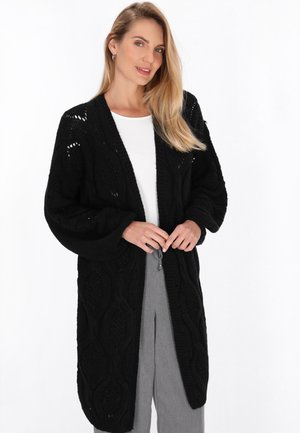 Črn pleteni cardigan z dolgim, odprtim dizajnom, teksturiranim kabelskim vzorcem, velikimi rokavi in zavezovanjem spredaj.