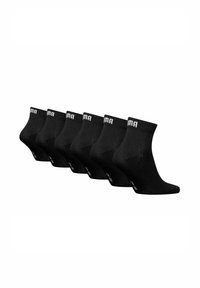 Schwarze Knöchelsocken in einer Reihe angeordnet, aus einem glatten Material gefertigt, mit einem gerippten Bund und einem weißen Logo auf dem Band. Set aus sechs Paar.
