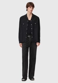 Sort skjorte med knapper og vestlig-inspireret skulderstykke, to brystlommer og sølvfarvede detaljer. Bruges over en sort t-shirt og kombineret med sorte jeans.