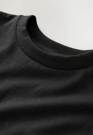 T-shirt in cotone nero con scollatura rotonda a costine. Caratterizzato da una texture liscia e un design semplice, che mette in risalto un aspetto pulito e sobrio.