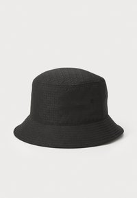 Cappello a secchiello nero con una texture trapuntata, caratterizzato da una corona rotonda e una visiera larga che si inclina verso il basso. Nessun hardware o accenti prominenti.