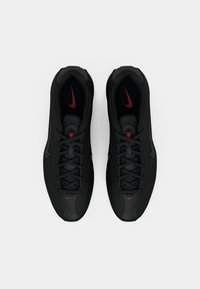 Par muškarci crnih Nike tenisica za trčanje s crvenim logotipima, prikazanih odozgo na bijeloj pozadini.
