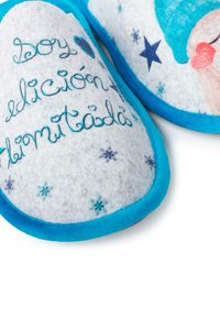 Filcové pantofle s bílým svrškem, který má modré š stitching, modrý lem a potisk rtů a hvězdiček. Text zní "Soy edición limitada."