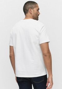 Hvid kortærmet t-shirt i bomuld med rund hals og standard pasform. Bagpå viser den et minimalistisk design uden dekorative elementer.