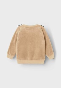 Lysebrunt fleece-sweatshirt med ribbede manchetter og kant, prydet med små dekorative sorte sløjfer på skuldrene. Blødt, struktureret stof.