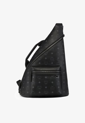 Sort tekstureret læder sling-rygsæk med diagonalt lynlås, frontlynlåslomme, subtil MCM-monogram og øverste håndtag.