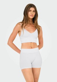 Λευκό ριμπ Μπραλέτ με V-Neck και ρυθμιζόμενες τιράντες, σε συνδυασμό με αντίστοιχα σορτς έως το μέσο του μηρού με αόρατη ζώνη.