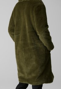 Olivengrøn faux pelsfrakke med blød tekstur, lange ærmer og en afslappet pasform, der har en simpel krave og sidelommer.