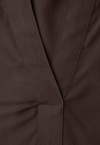 Tissu marron à finition mate, présentant un décolleté en V et des coutures soignées le long des bords, mettant en valeur des éléments de design sur mesure.