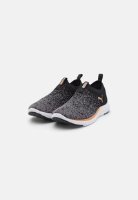 Des chaussures slip-on tricotées en noir et gris avec une semelle blanche, présentant un motif dégradé subtil et un accent doré au talon.