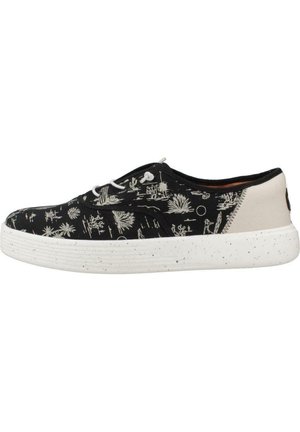 Baskets basses noires avec motifs de plantes désertiques blanches, lacets blancs, talon beige et semelle épaisse blanche mouchetée.