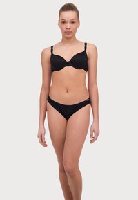 Black lingerie set featuring a padded bra with lace trim and matching thong. Non-adjustable scalloped straps and a smooth texture.