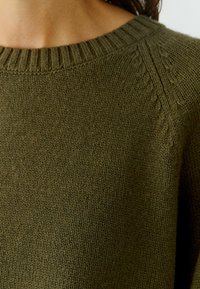 Olijfgroen gebreid sweater met een rechttoe rechtaan halslijn en textuurdetails op de schouders. Zacht, middelzwaar materiaal.