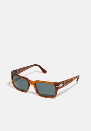 Occhiali da sole tartaruga marrone con lenti scure, forma rettangolare, dettagli in metallo sulle tempie e rifiniture testurizzate ai lati.