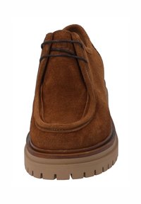 Scarpa in suede marrone con punta arrotondata, dettagli cuciti e suola in gomma beige spessa. Presenta lacci marroni e un colletto imbottito.