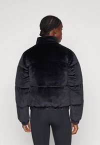 Giacca puffer blu navy realizzata in morbido materiale peloso, con colletto alto, polsini elastici e orlo aderente. Presenta un design trapuntato.