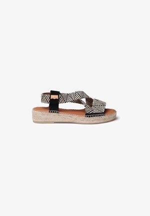 Espadrilové sandály s křížovými černobílými pásky, pletenou jutuovou podrážkou, s hladkým hnědým vkladem a černými akcenty.