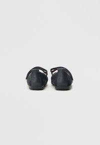 Czarne buty z siateczki i skóry z regulowanymi paskami. Okrągły nosek i płaska podeszwa. Teksturowana powierzchnia z kontrastowymi akcentami.