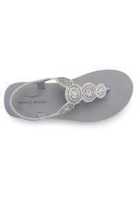 Grijze flip-flops met een decoratieve zilveren beugel met ronde edelsteendetails, platte zool en een gladde, textuurvrije inlegzool.