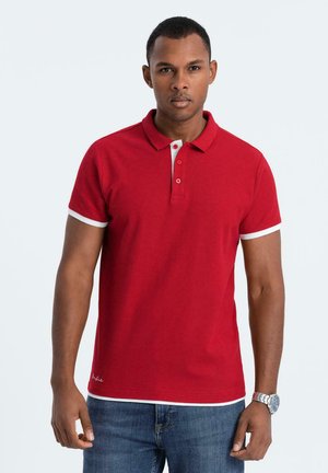 Rode polo met een gekleurde halslijn, witte accentafwerking op de mouwen en de knoopsluiting, gemaakt van katoen, gecombineerd met blauwe denim jeans.