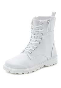 Bottine blanche en toile avec bout arrondi, devant à lacets, fermetures éclair sur le côté et semelle en caoutchouc texturé pour une bonne traction.