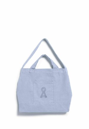 Hellblaue Canvas-Tragetasche mit kurzen und langen Griffen, Fronttasche und besticktem schlüssellochförmigem Logo auf weißem Hintergrund.