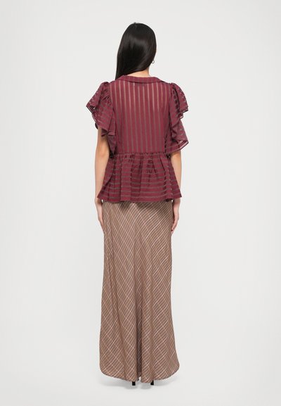 Bordeaux peplum top met gekruiste mouwen en gestreept patroon, gecombineerd met een bruine geruite maxi rok met een vloeiende silhouet.