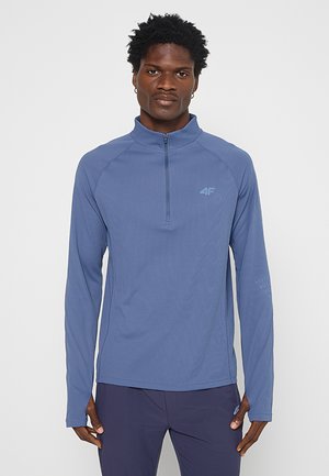 Długi rękaw, sportowa bluzka z zamkiem błyskawicznym na ćwiartkę w kolorze niebieskim, z teksturowanej tkaniny i subtelnym logo na piersi, z rękawami raglanowymi dla swobody ruchów.