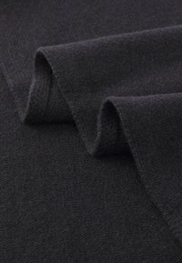 Tissu en laine noire qui se drape avec une texture douce, présentant une surface lisse et légèrement texturée et des bords roulés pour une touche de détail.