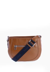Bolso cruzado de cuero marrón con forma curva, que presenta un bolsillo delantero con cremallera y una correa ajustable negra con detalles del logo.