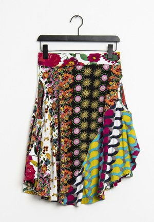 Jupe colorée à motifs comprenant des motifs floraux, des designs géométriques et des accents vibrants en jaune, bleu, rouge et noir. Tissu plissé.