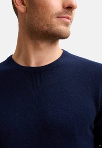 Maglione girocollo blu navy realizzato in morbido tessuto a maglia, con scollatura a costine e cuciture rinforzate sulle spalle per un tocco di dettaglio.