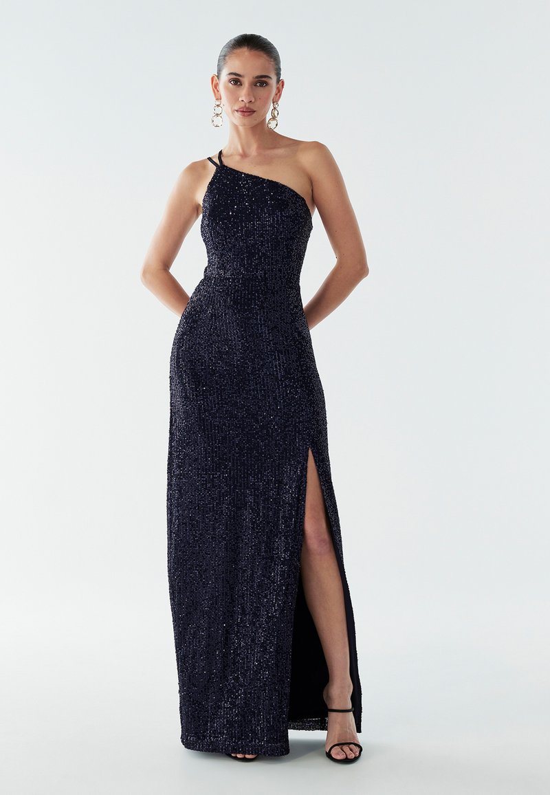 Námornícky šaty na večer s trblietavými detailmi, jedným ramienkom, vysokým rozparkom a priliehavým strihom. Obsahujú jemný lesk a hladkú textúru.