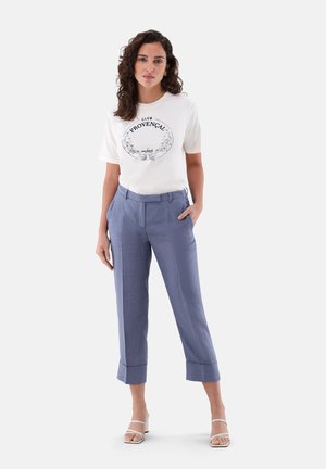 Hellblaue, maßgeschneiderte Hosen mit aufgerollten Säumen und seitlichen Taschen, kombiniert mit einem cremefarbenen T-Shirt mit einem schwarzen Grafikdruck.