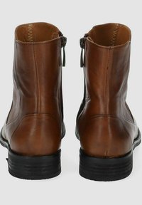 Stivali ankle in pelle marrone con una texture liscia, chiusura a zip e tacco impilato nero, caratterizzati da un design minimalista e senza dettagli di hardware visibili.