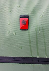Groene gestructureerde stof met waterdruppels, met een zwart en rood "Gladiator" logo op een zwarte strook onderaan.