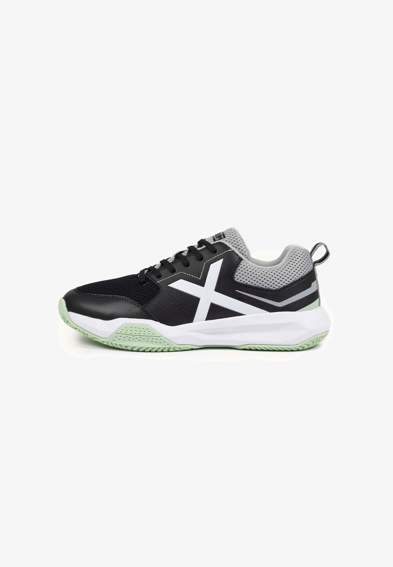 Chaussure de sport noire avec un matériau texturé, des accents en mesh gris, des détails blancs et une semelle vert menthe. Présente un design à lacets et une languette de tirage.