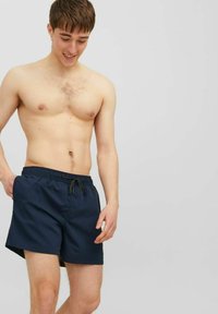 Pantaloni da bagno blu navy realizzati in tessuto leggero, dotati di una vita elastica con cordino e tasche laterali.